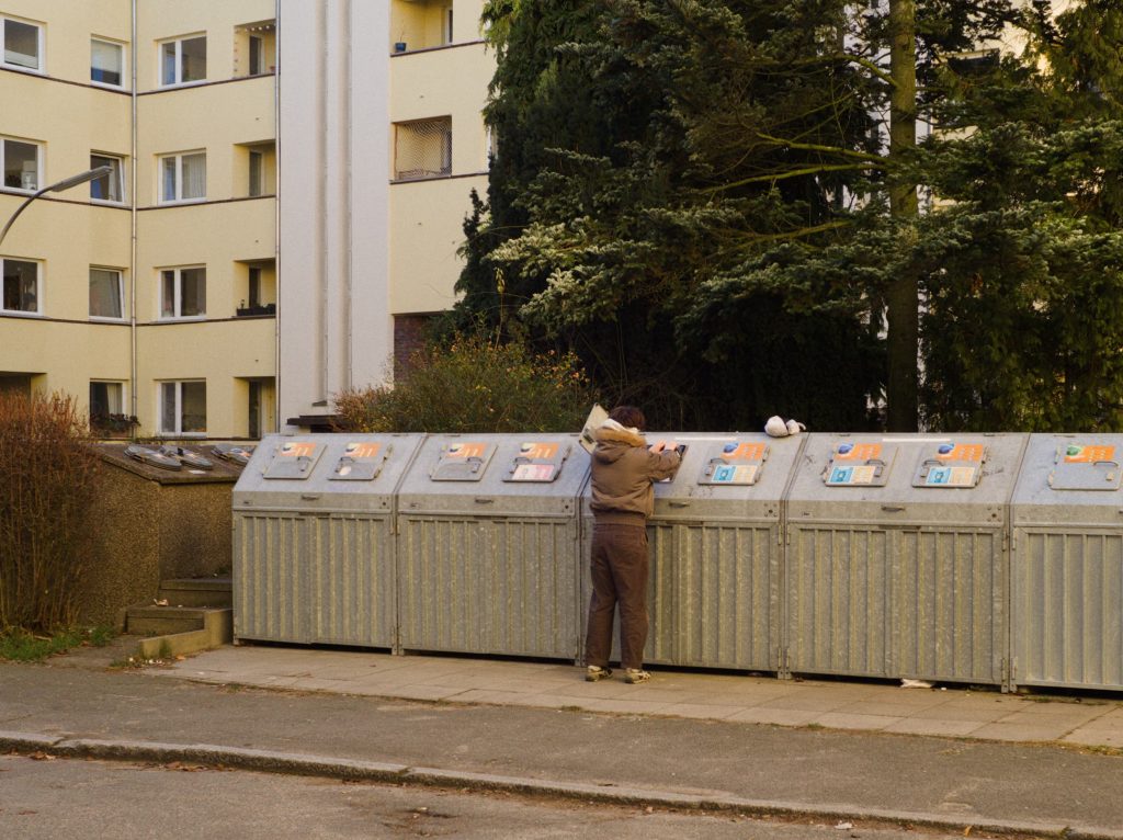 Ein Mann vor Mülltonnen in einem Innenhof
