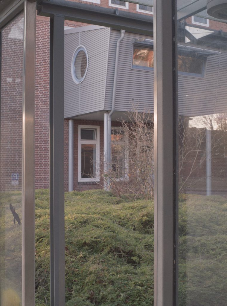 Ein Gebäude mit Anbau hinter einer Grünfläche